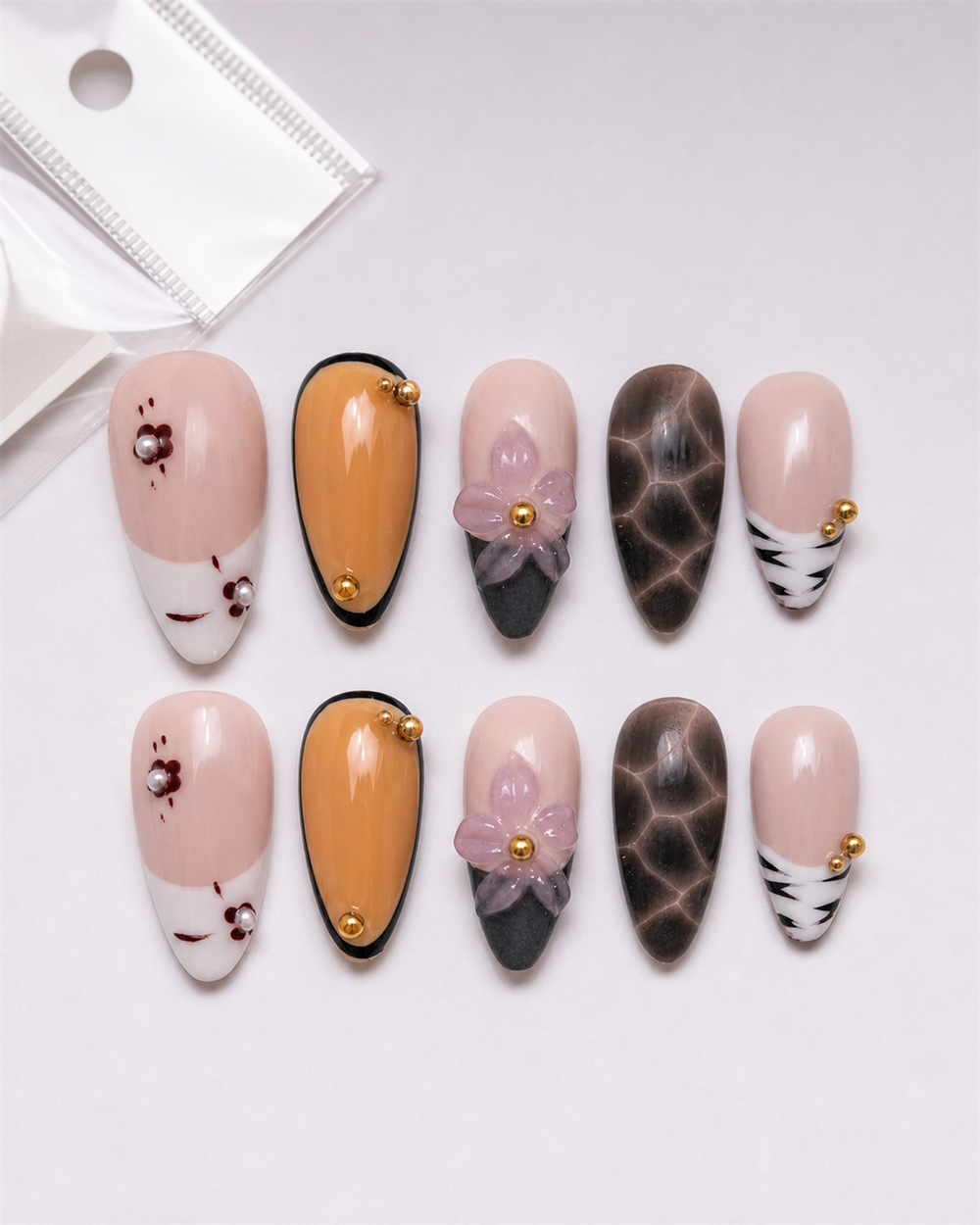Ten Amber Noir Floral almond press-on nails arranged as a complete set.